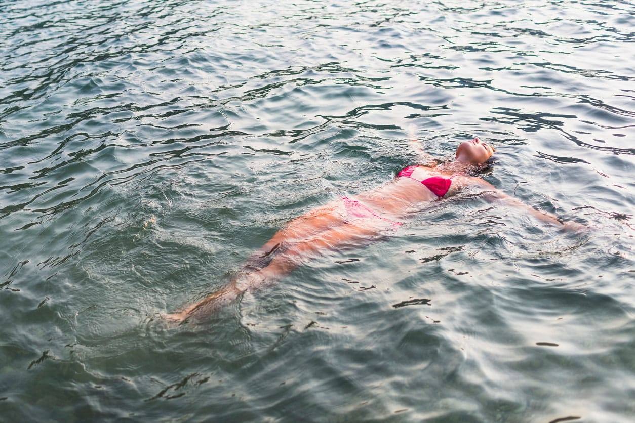 Frau treibt genüsslich auf dem Rücken im Wasser